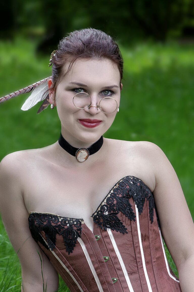 A woman in a corset and feathers posing in the grass